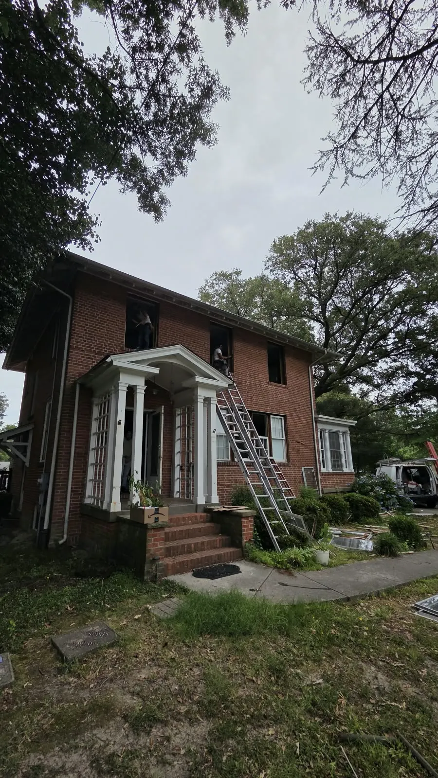 Two-story brick home with a ladder set up for exterior work in Hampton, VA