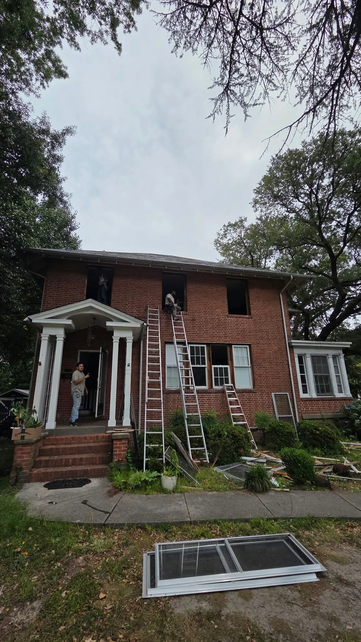 Brick colonial with new windows and a ladder during window installation in Hampton, VA