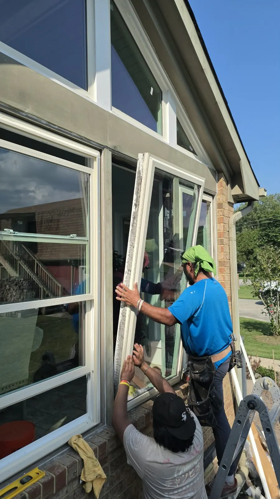 Two crew members installing a replacement window from a ladder in Hampton, VA