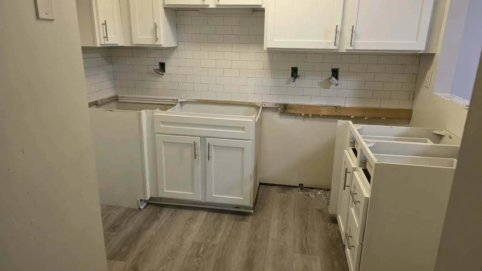 White kitchen cabinets with subway tile backsplash and plank flooring in Hampton, VA